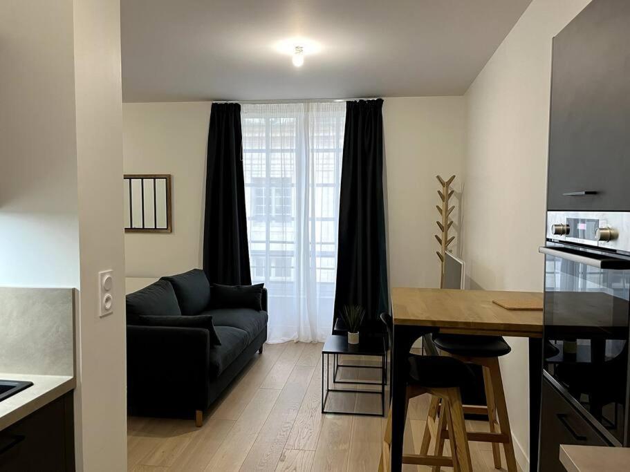 een woonkamer met een bank en een tafel bij Le Bijou du Martroi in Orléans