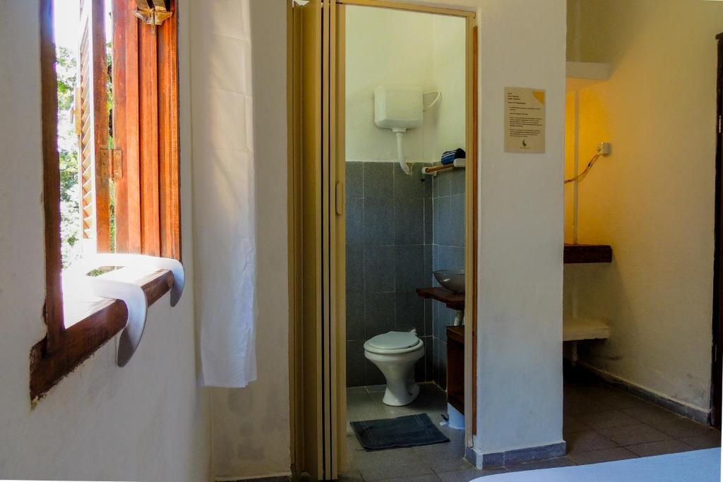 a bathroom with a toilet and a window at Recanto da Floresta Suites in Ubatuba