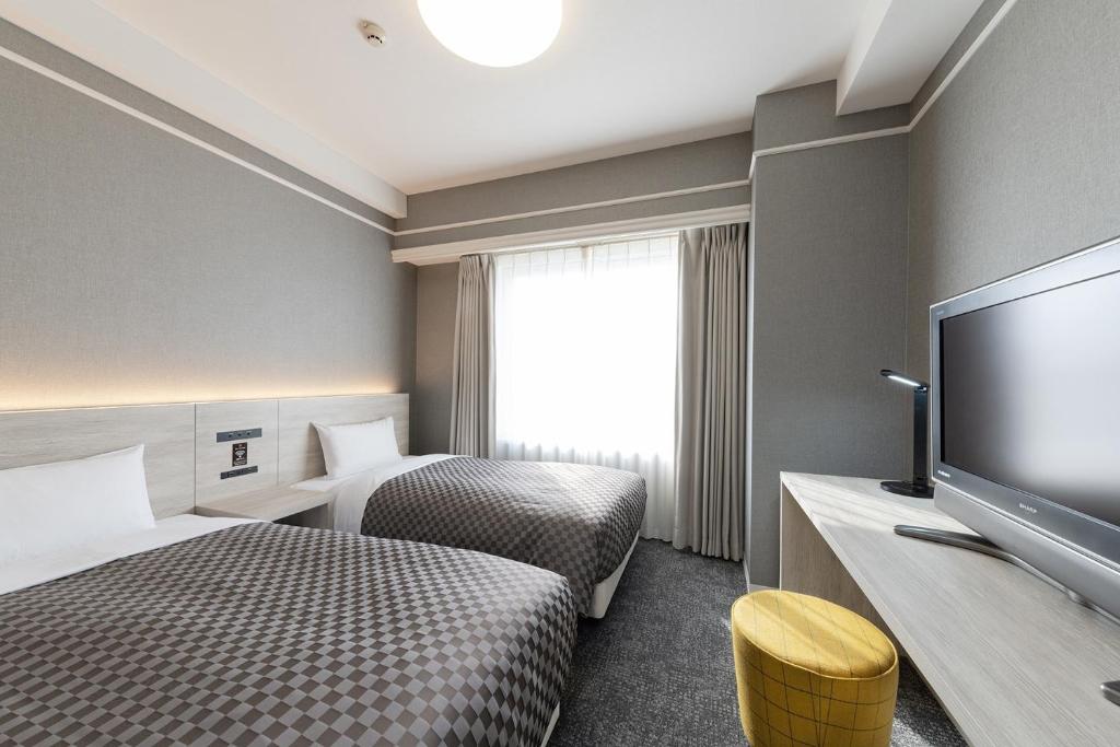 ein Hotelzimmer mit 2 Betten und einem Flachbild-TV in der Unterkunft The One Five Garden Kurashiki - Vacation STAY 40165v in Kurashiki