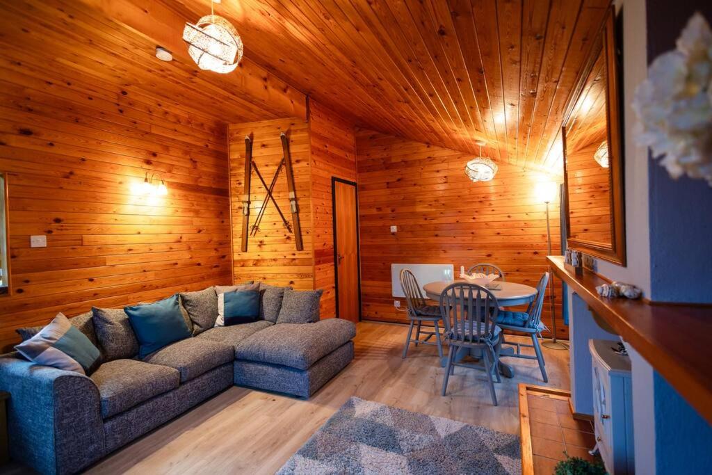 een woonkamer met een bank en een tafel bij Rural Log Cabin Retreat near Coed y Brenin by Seren Short Stays in Ffestiniog