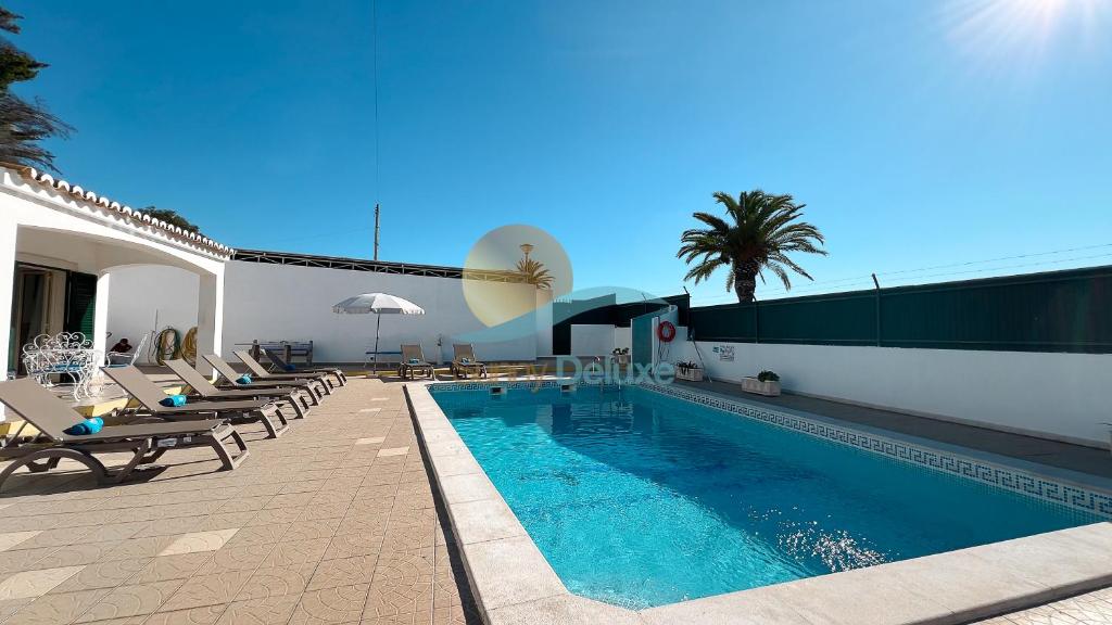 - une piscine avec des chaises longues à côté d'un bâtiment dans l'établissement Villa Bea by Sunny Deluxe, à Albufeira