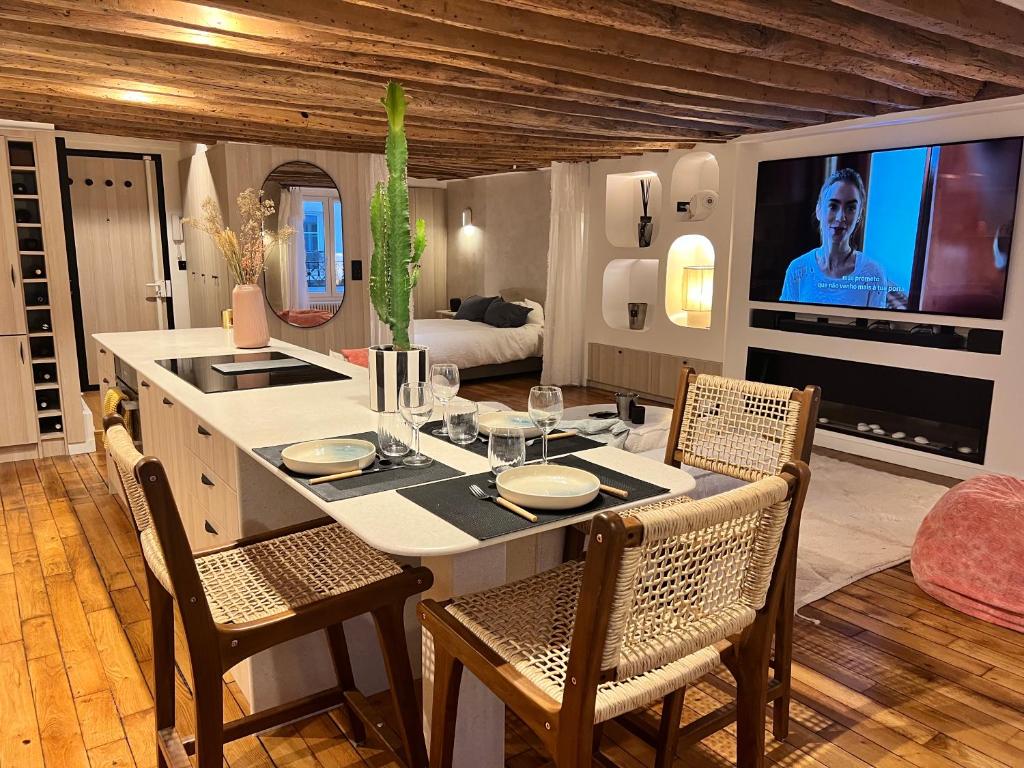 une cuisine avec une table avec des chaises et une télévision dans l'établissement Appartement luxe Louvre Paris, à Paris