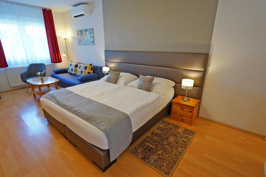 a bedroom with a large bed and a blue couch at Apartman Brigitte Bükfürdő in Bük