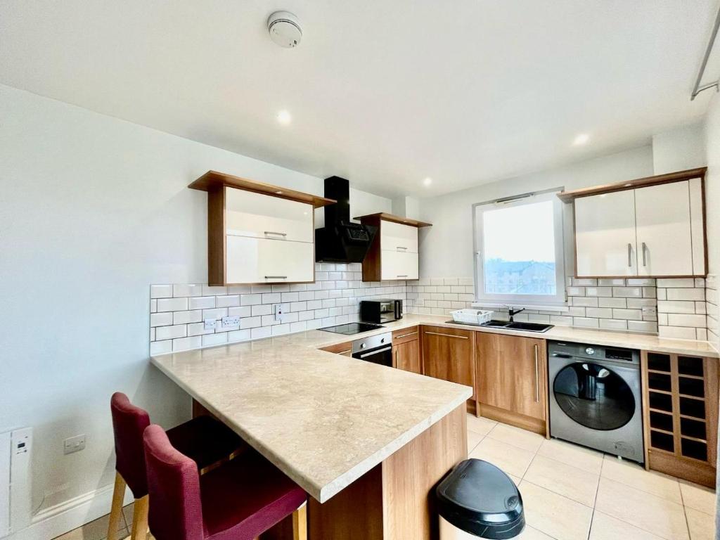 a kitchen with a counter and a washer and dryer at London Modern Flat near transports in London
