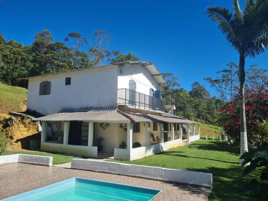 une maison blanche avec une piscine en face de celle-ci dans l'établissement Lindo sitio inserido a natureza, à Mogi das Cruzes