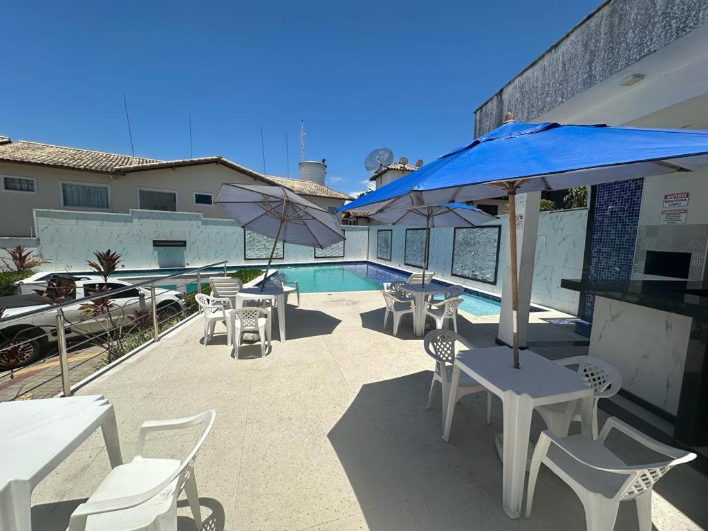 a patio with tables and umbrellas and a pool at Apartamento Porto Villa dos Diamantes 22 in Porto Seguro