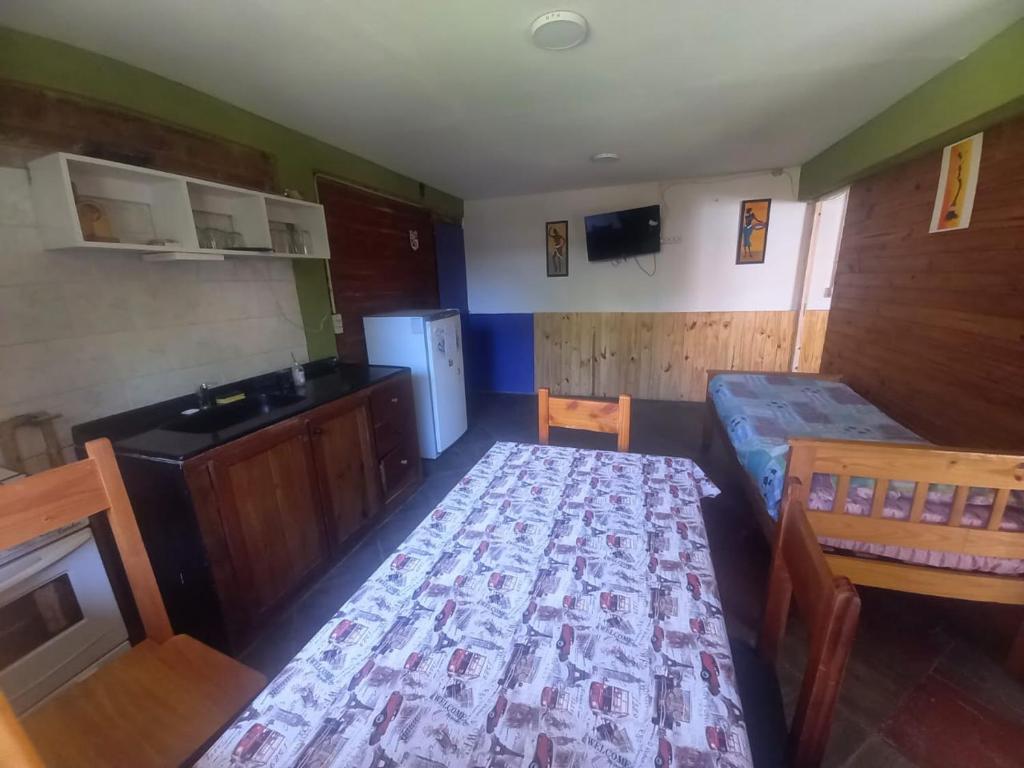 a room with a bed and a table and a kitchen at Dos Soles in El Bolsón
