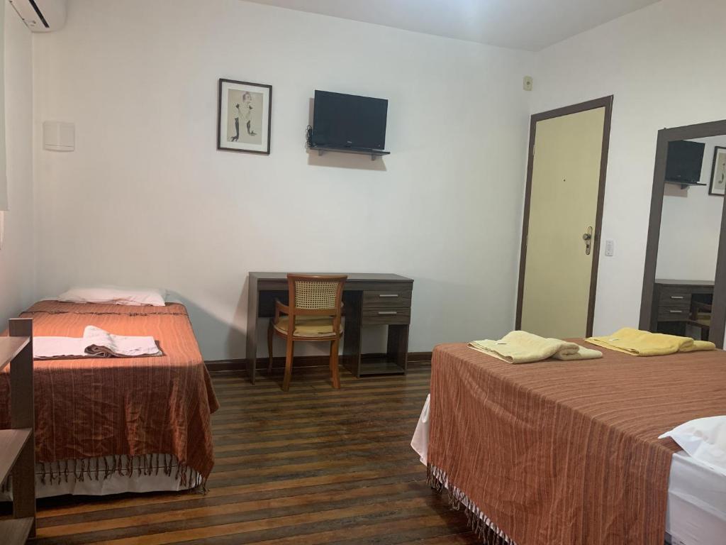 a hotel room with two beds and a desk at Casa do Sol Fortaleza in Fortaleza