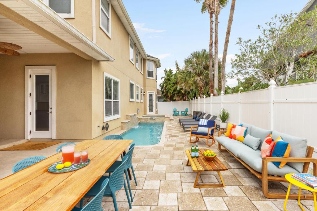 un patio con sofá, mesas y piscina en Vilano Villa en St. Augustine
