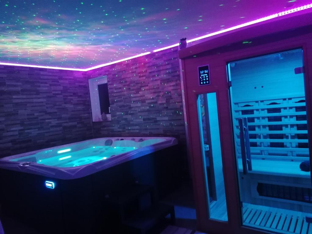 une salle de bains avec jacuzzi et lumières violettes dans l'établissement Aux Charmes de la Vallée, à Béthisy-Saint-Pierre