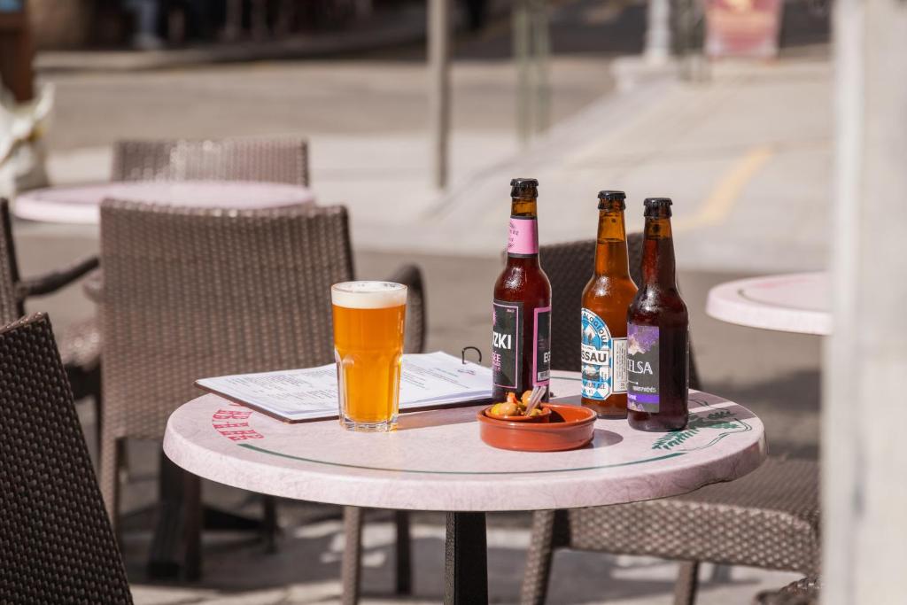 einen Tisch mit drei Flaschen und ein Glas Bier in der Unterkunft Hôtel Le Bois Joli in Cauterets