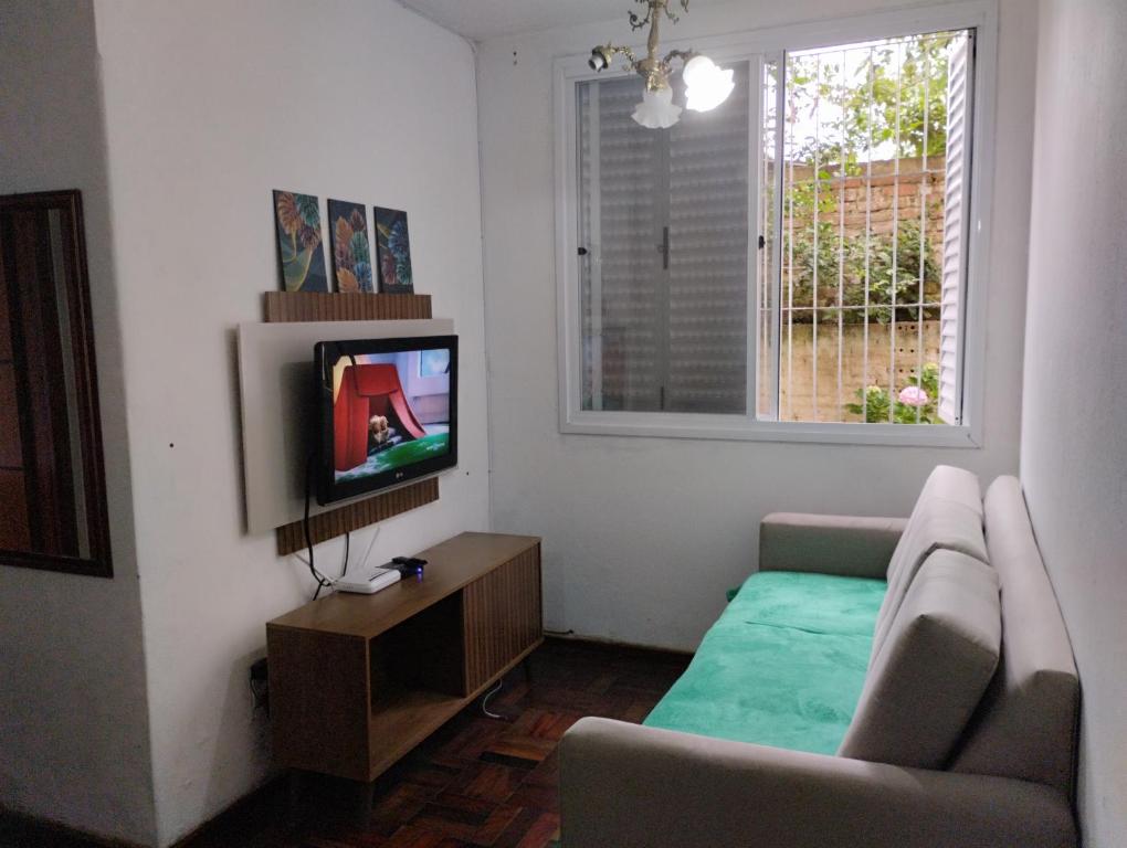 uma sala de estar com um sofá e uma televisão em Apartamento 2 quartos em Pelotas