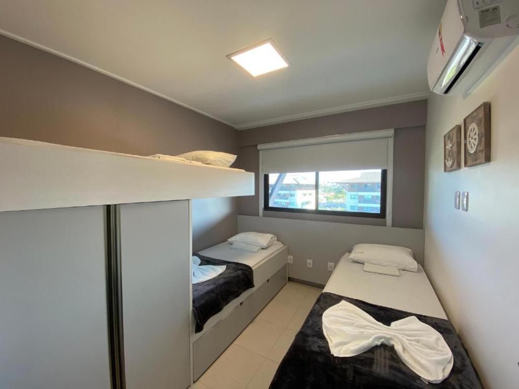 a small room with two beds and a window at Cupe Beach Living Concept 304E in Porto De Galinhas