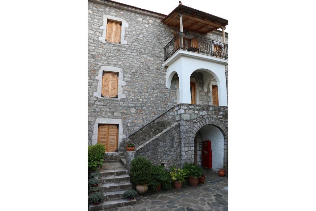een stenen huis met een trap en een balkon bij Maleatis Apollo Guesthouse in Kosmás
