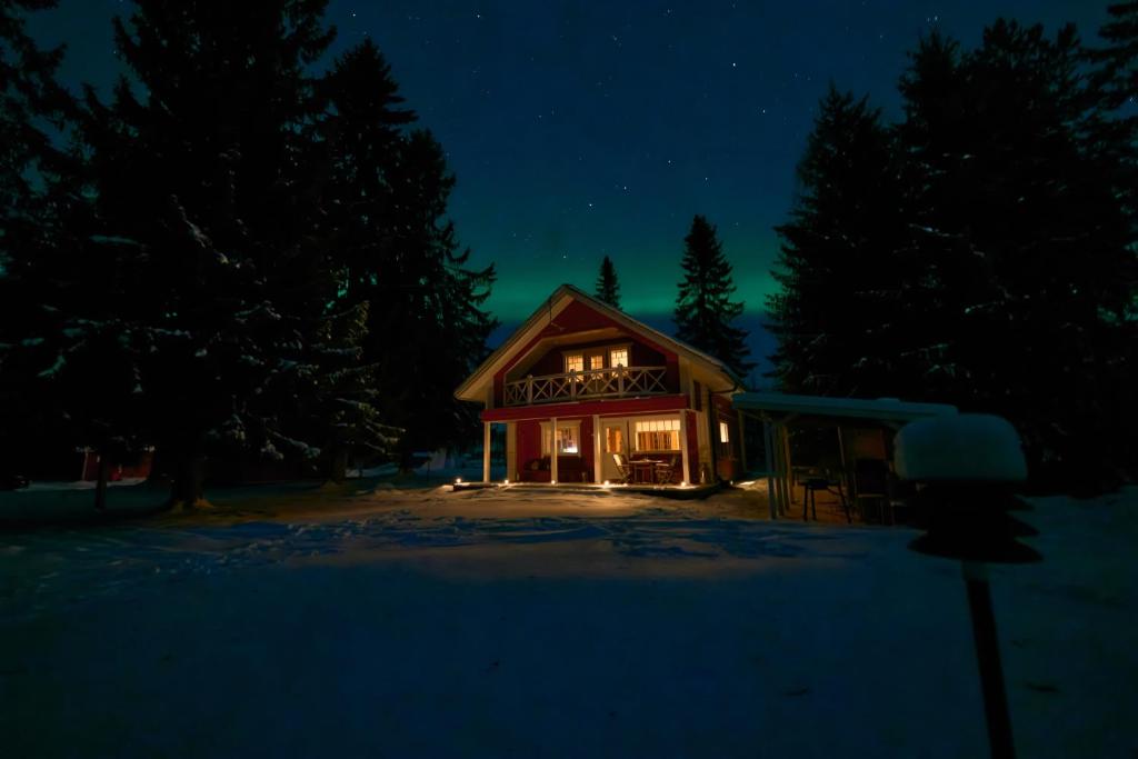 a house lit up at night in the snow at Iisland Uoma waterfront house, sauna in Ii in Ii