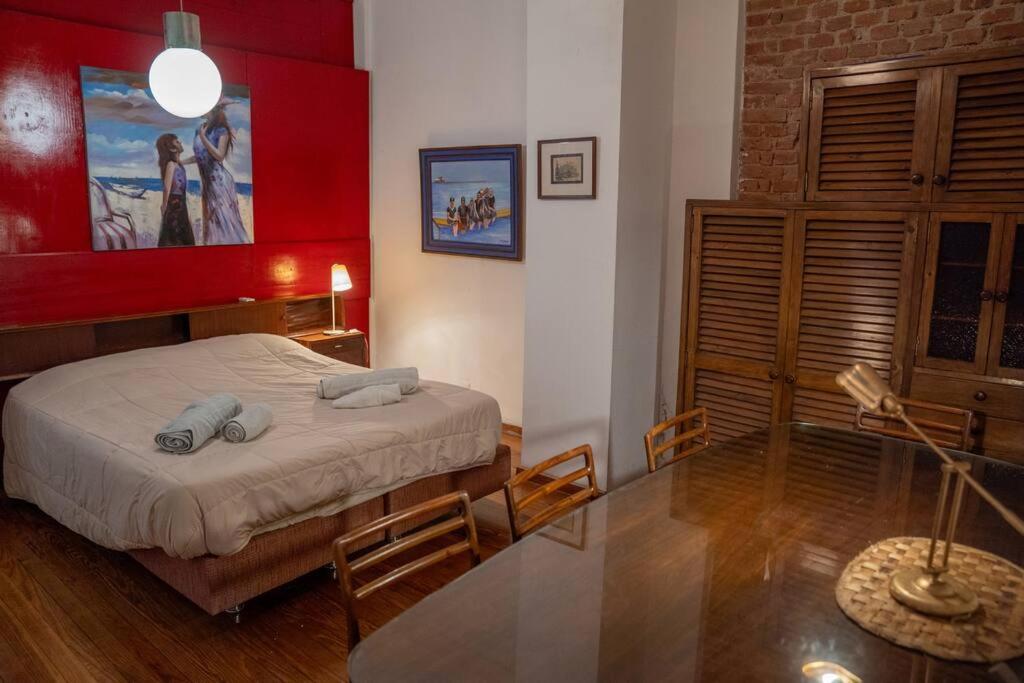 1 dormitorio con cama y pared roja en The Wall Montevideo [004] Loft in the Old Town en Montevideo
