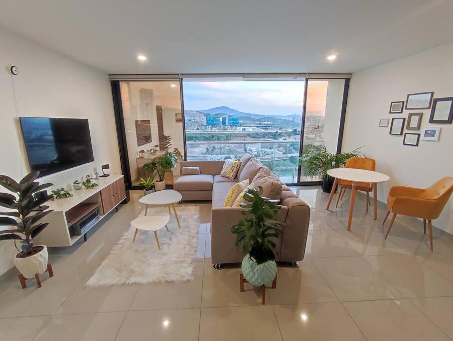 a living room with a couch and tables and a tv at Loft con Vista Panoramica Milenio lll Queretaro in Querétaro