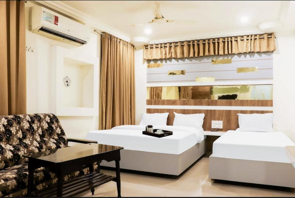 une chambre d'hôtel avec deux lits et une chaise dans l'établissement Menaka, à Vijayawada