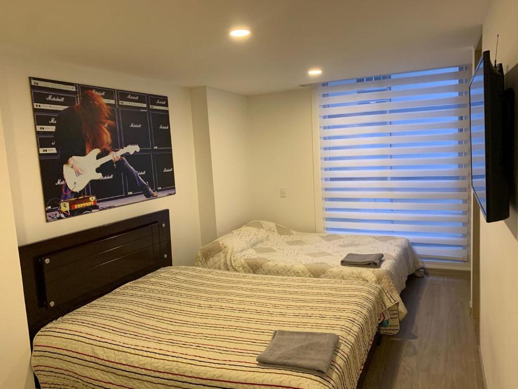 - une chambre avec 2 lits et une image d'une guitare dans l'établissement Alojamiento tipo LOFT completo en barrio Las Aguas, à Bogotá