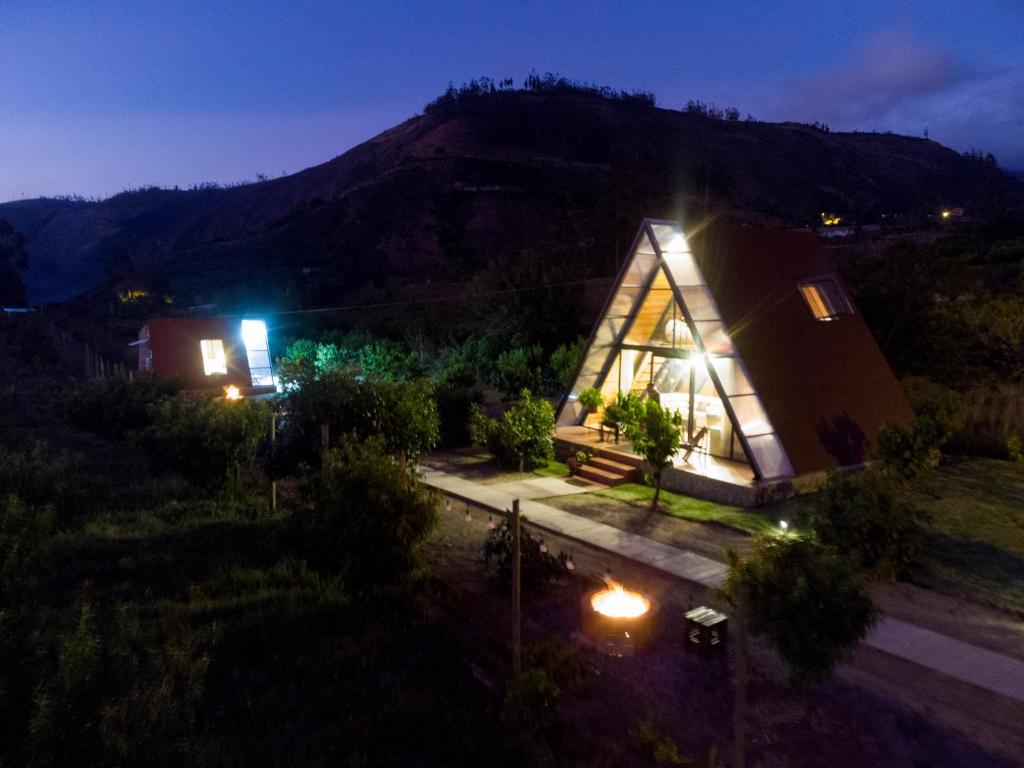 une petite maison avec des lumières allumées la nuit dans l'établissement Glamping Guaytambos Lodge, à Patate