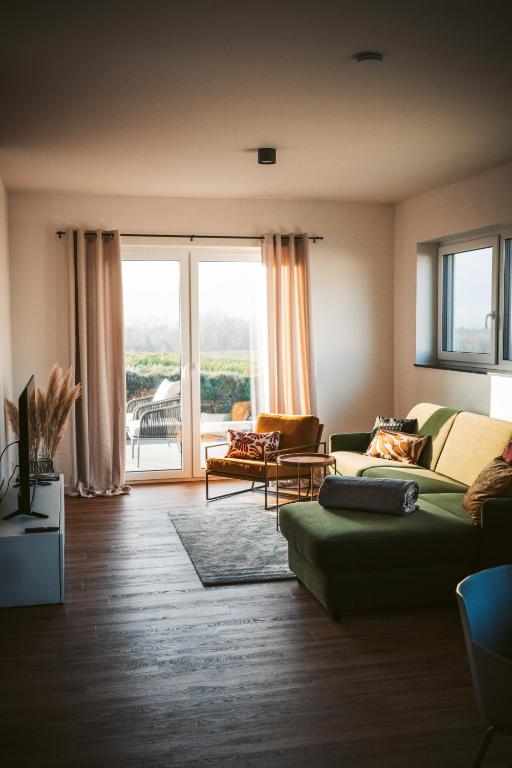a living room with a green couch and a large window at Hunsrück Lodge in Mittelstrimmig