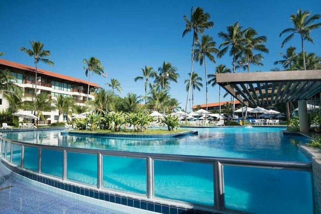 - une piscine dans un complexe avec des palmiers dans l'établissement Marulhos Suites Resort, à Porto de Galinhas