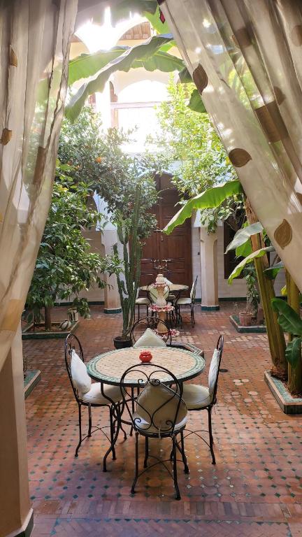 an outdoor patio with tables and chairs and plants at Riad Tidar by Phoenix in Marrakesh