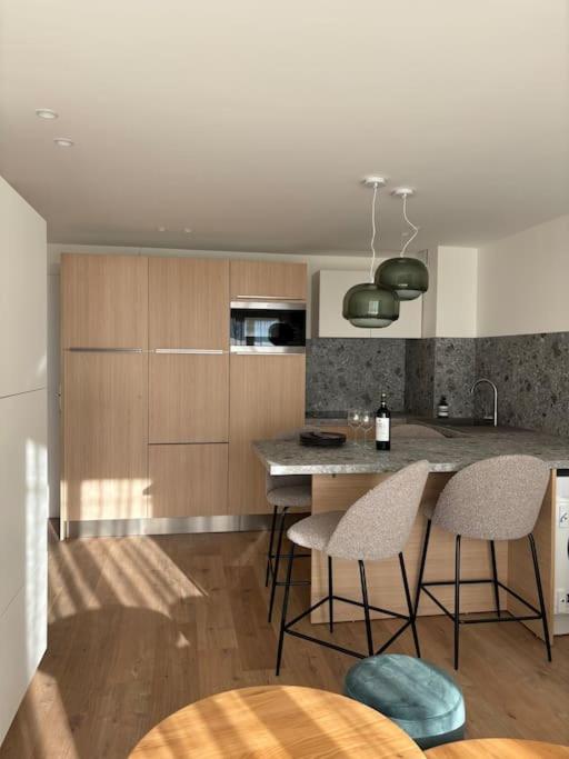 une cuisine avec un îlot doté de chaises et d'un comptoir dans l'établissement Appartement Les Hirondelles, à Aix-les-Bains