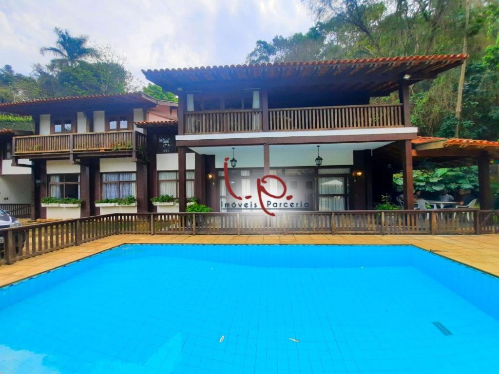 a villa with a swimming pool in front of a house at Pousada Demuner's House - Espaço Aconchegante Itaipava in Petrópolis