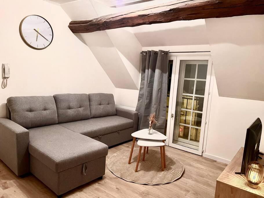- un salon avec un canapé et un réveil sur le mur dans l'établissement Appartement Cosy Nemours, à Nemours