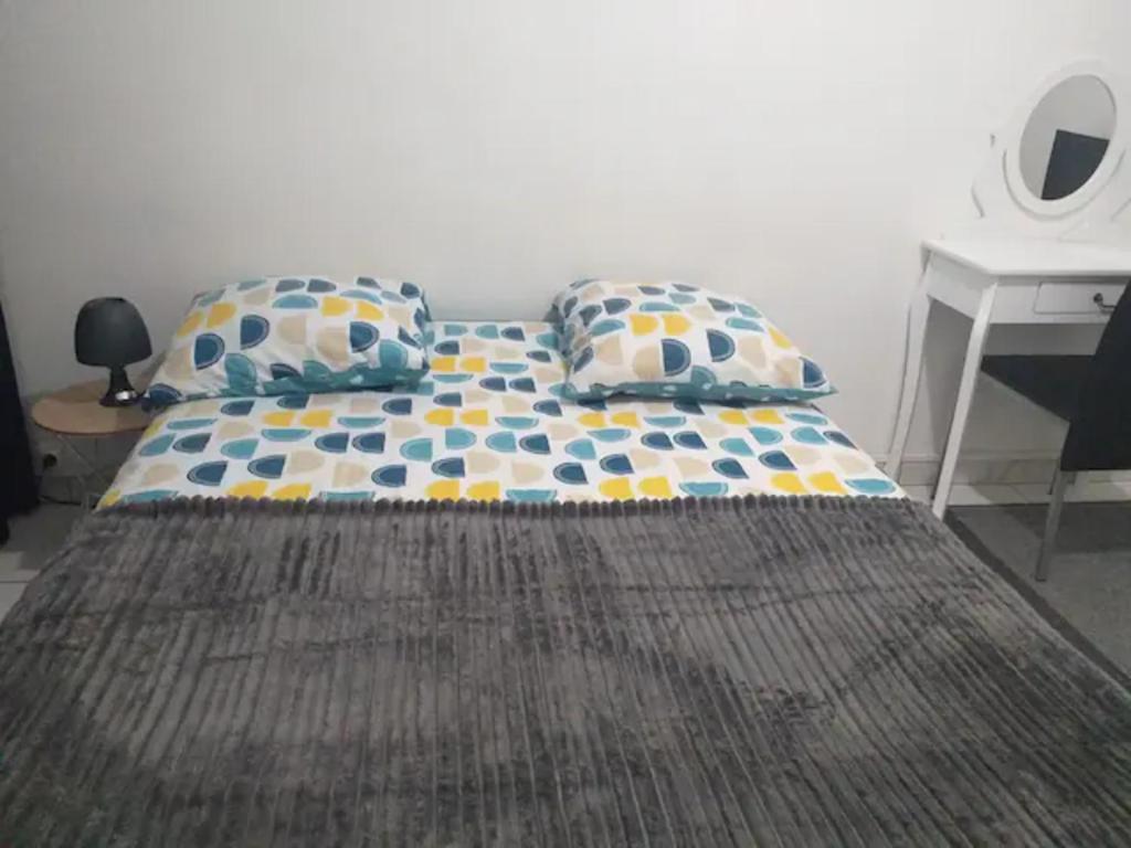 a bed with two pillows and a desk in a room at 3 chambres à louer dans l'appartement deux pas à Tramway2 in Colombes