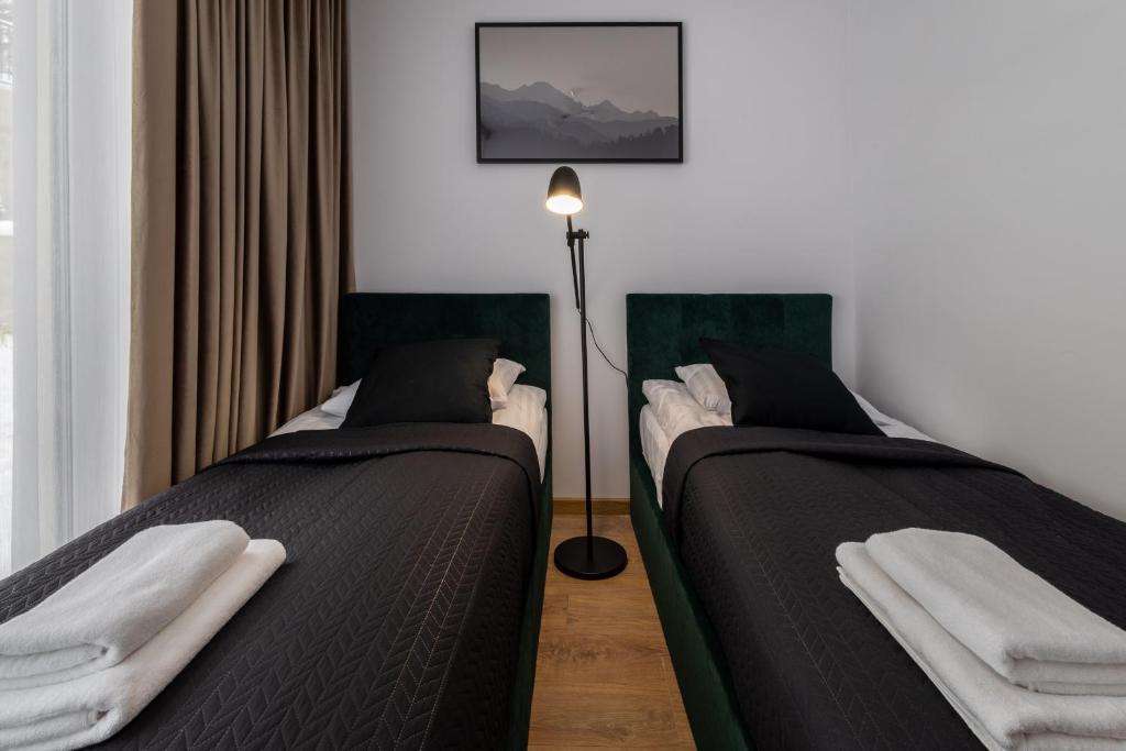 two twin beds in a room with a lamp at Krynica Apartamenty Apartament z sypialnią Centrum Cicha 12 in Krynica Zdrój