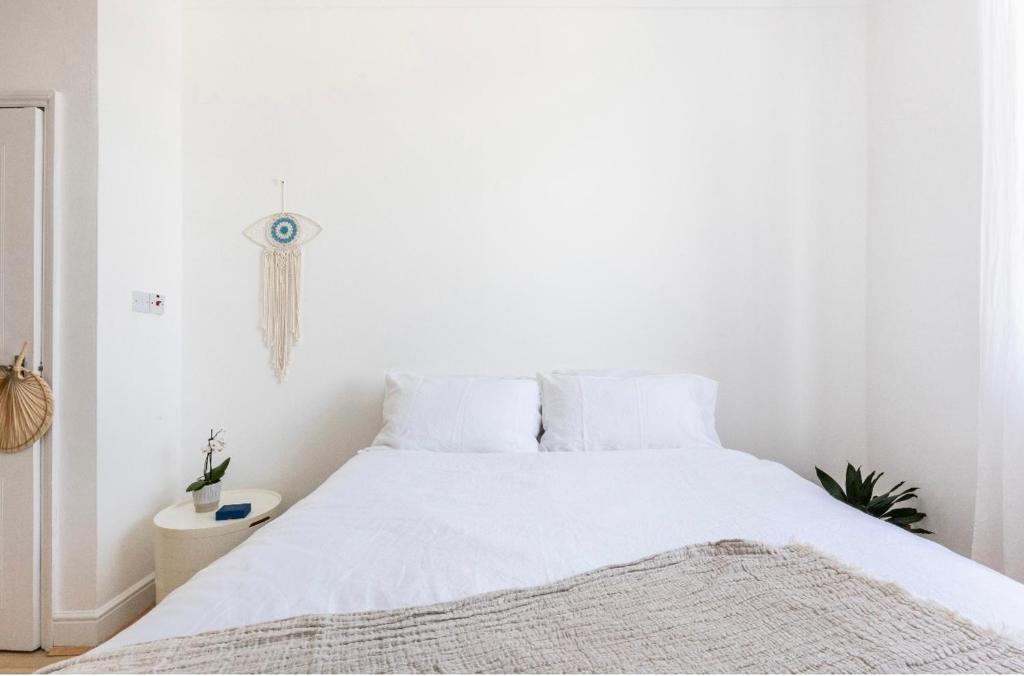a white bedroom with a large bed with white sheets at Loft-style apartment with large roof terrace in London