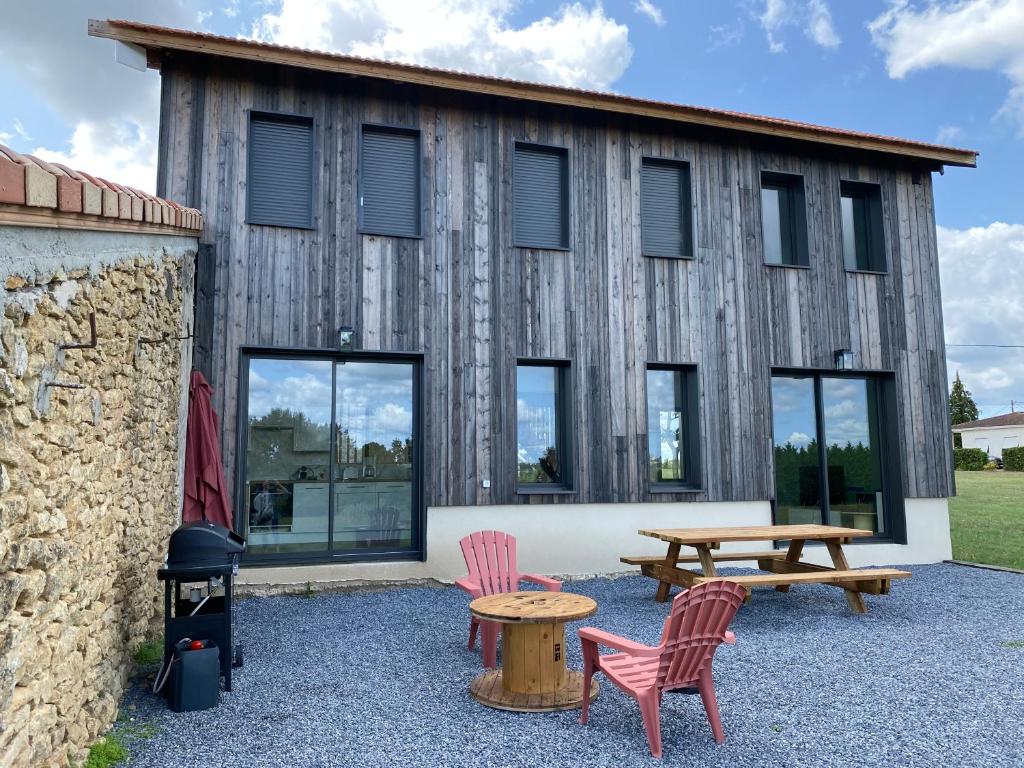 - un bâtiment en bois avec une table de pique-nique et des chaises dans l'établissement Séchoir rénové, vue panoramique et nombreux jeux, à Saint-Pierre-de-Mons