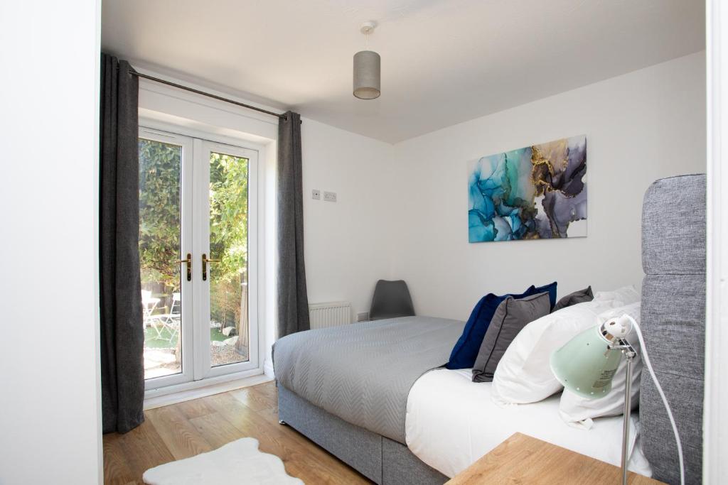 a white bedroom with a bed and a window at Apartment in the heart of Old Town Beaconsfield in Buckinghamshire