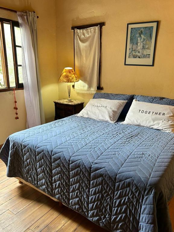a bedroom with a bed with a blue comforter at Departamento serrano in Nono