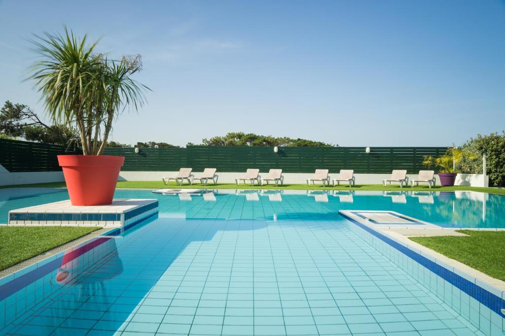 uma piscina com cadeiras e uma palmeira ao lado em Atlanthal em Anglet