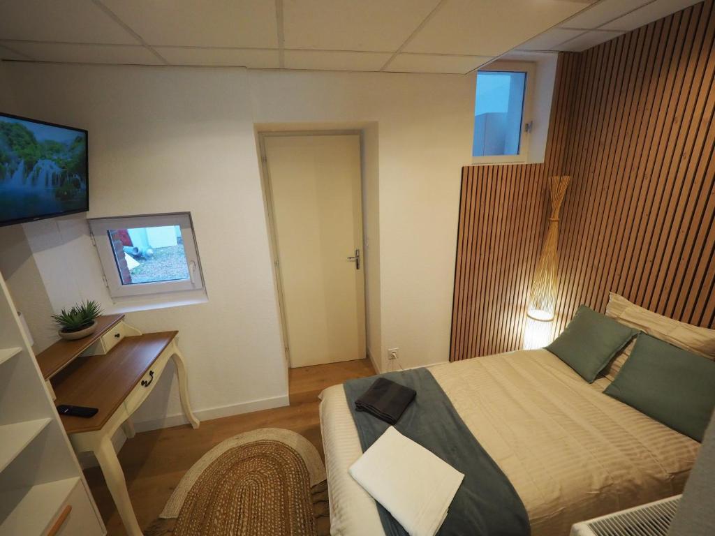 a bedroom with a bed and a desk and a television at Appartement meublé 4 - 15 min Dampierre - 25 min Belleville - WIFI in Gien