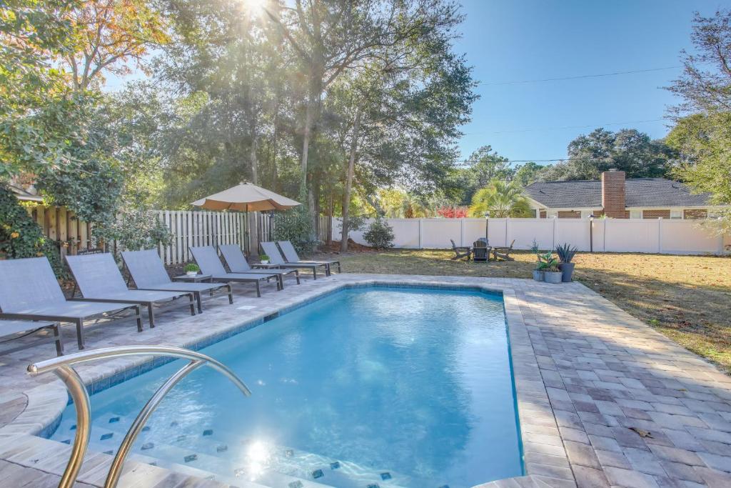 a swimming pool with lounge chairs next to a backyard at Myrtle Beach Home with Saltwater Pool, Walk to Beach in Myrtle Beach
