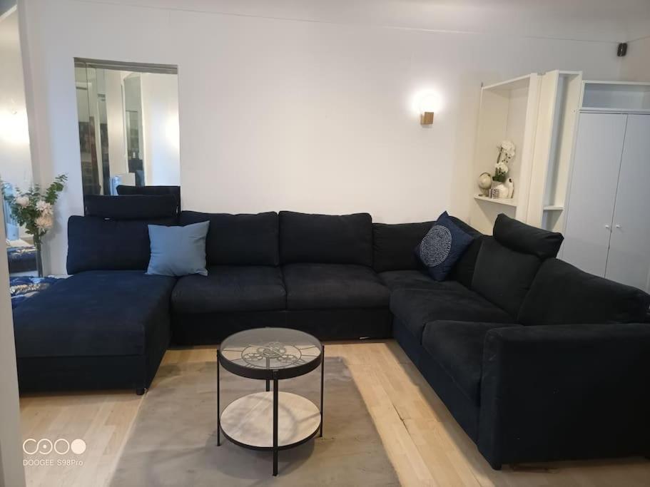 un salon avec un canapé noir et une table dans l'établissement Aramis Colibri 72m2, lit king-size, baignoire duo hôte non professionnel, à Paris