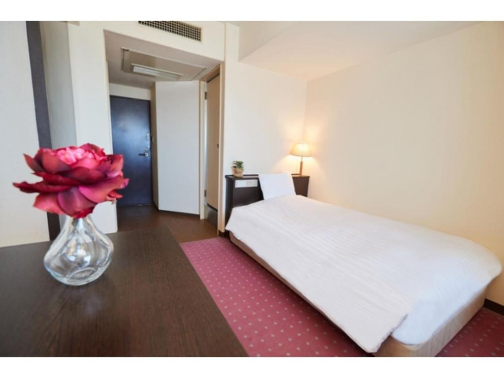 a bedroom with a white bed and a vase with a flower at Hotel Crystal Palace - Vacation STAY 61203v in Hitachinaka