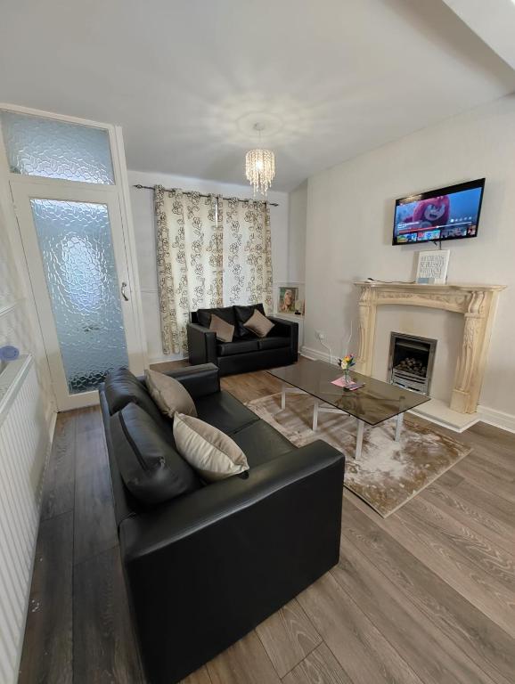 a living room with a black couch and a fireplace at Anstuns LODGE in Liverpool