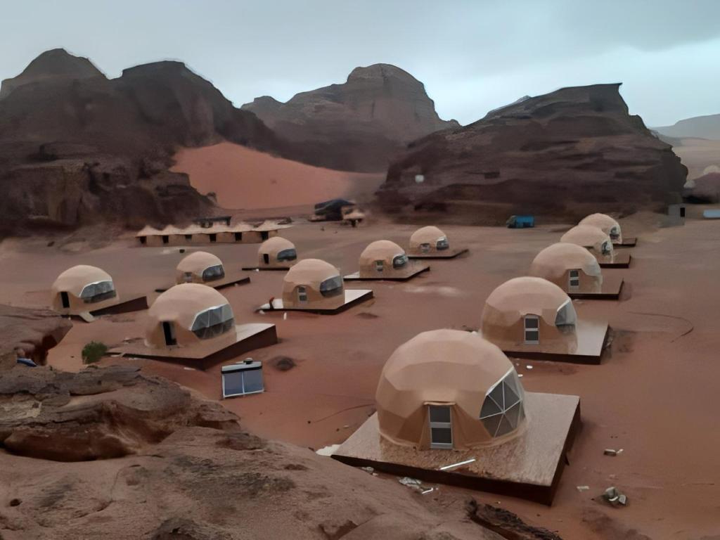 a group of domes in a desert with mountains at wadi novas camp in Wadi Rum