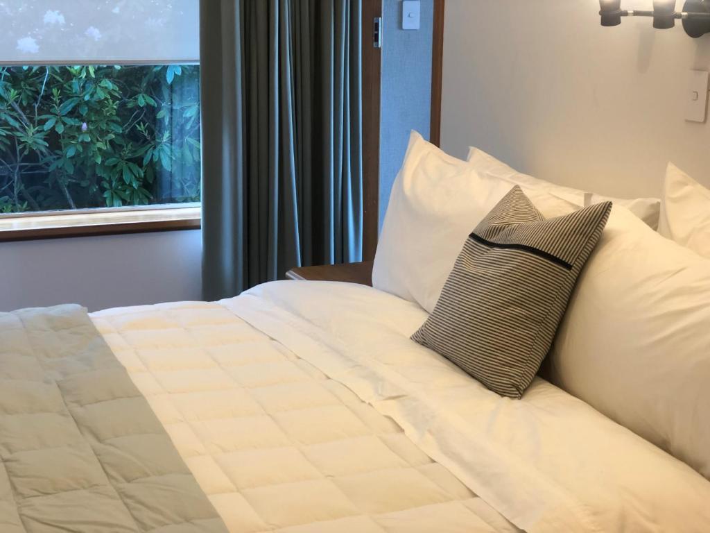 a bedroom with a bed with white pillows and a window at Seaview Cottage in Oamaru