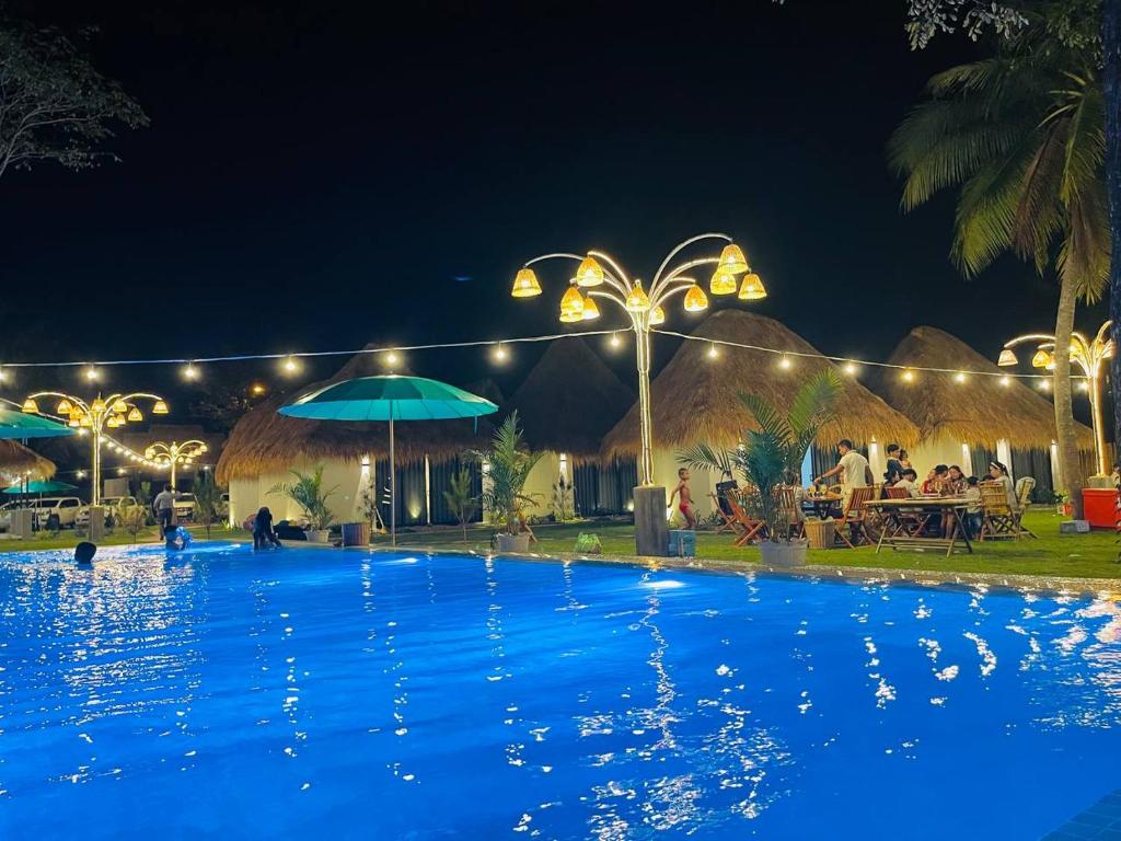 a large swimming pool at night with people sitting outside at SEA SAND RESORT in Kampot