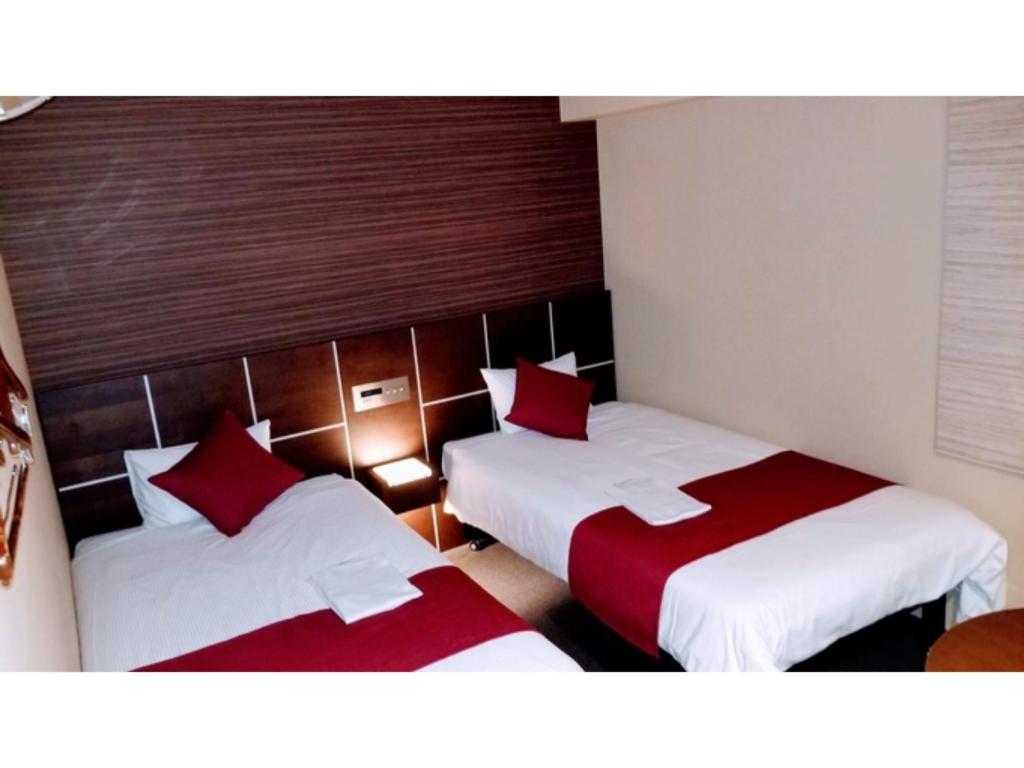 2 letti in camera con cuscini rossi di My Hotel Okazaki - Vacation STAY 40799v a Okazaki