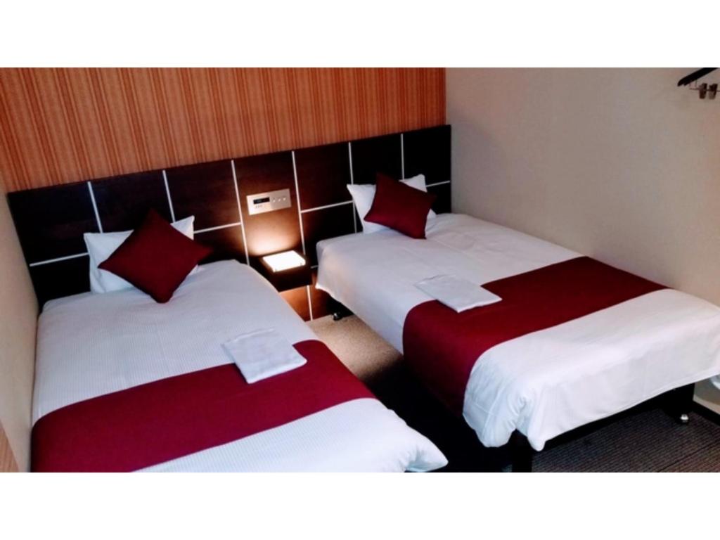 two beds in a room with red and white sheets at My Hotel Okazaki - Vacation STAY 40801v in Okazaki