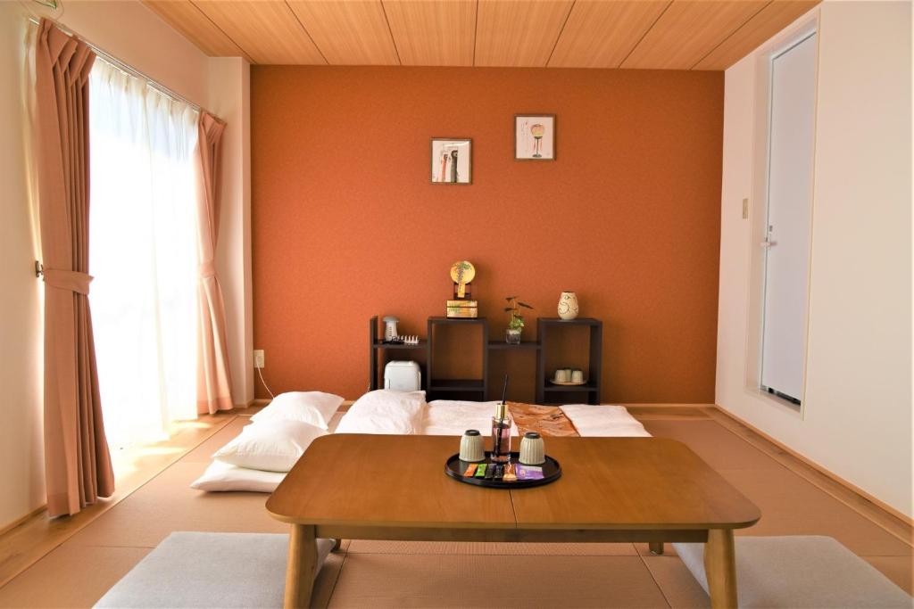 a living room with orange walls and a table at YūshukuFushimi Inari - Vacation STAY 41351v in Kyoto