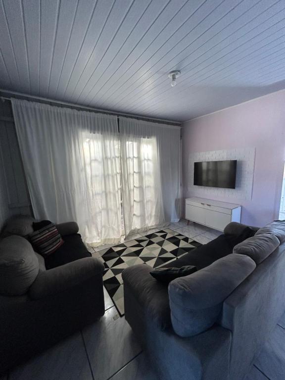 - un salon avec deux canapés et une télévision à écran plat dans l'établissement Aluguel casa para temporada, à Itapema