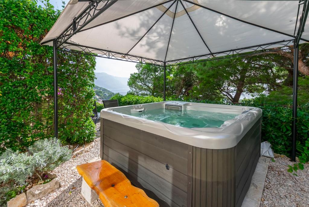 a hot tub with an umbrella in a garden at Apartments Olive sea view in Mimice